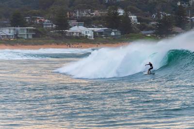 Early morning seascape with surfer catching a wave