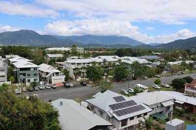 Buildings, trees and cars along a road with mountains in the background in Cairns, Queensland, Australia