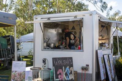 Food vendor preparing meals inside a mobile catering trailer at a community market.